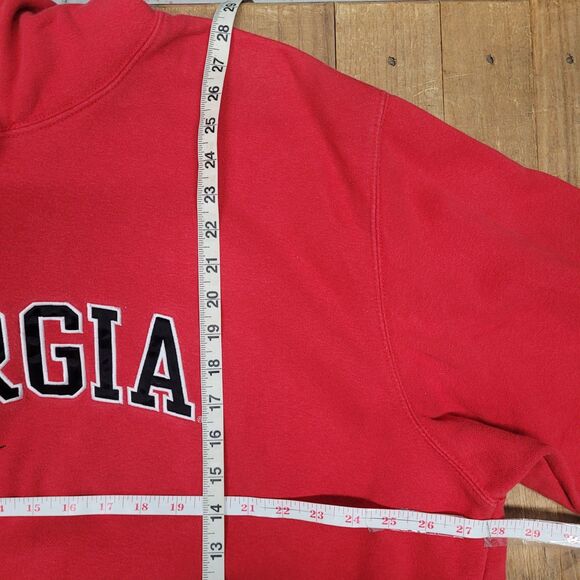 Red center swoosh Nike Bulldogs hoodie with black and white Georgia text and measuring tape on wooden floor